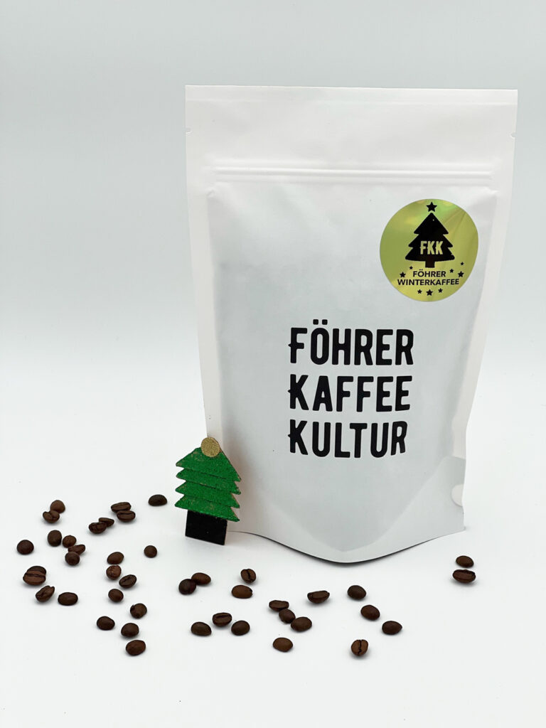 Beutel unseres Föhrer Winterkaffees neben Kaffeebohnen und weihnachtlicher Deko