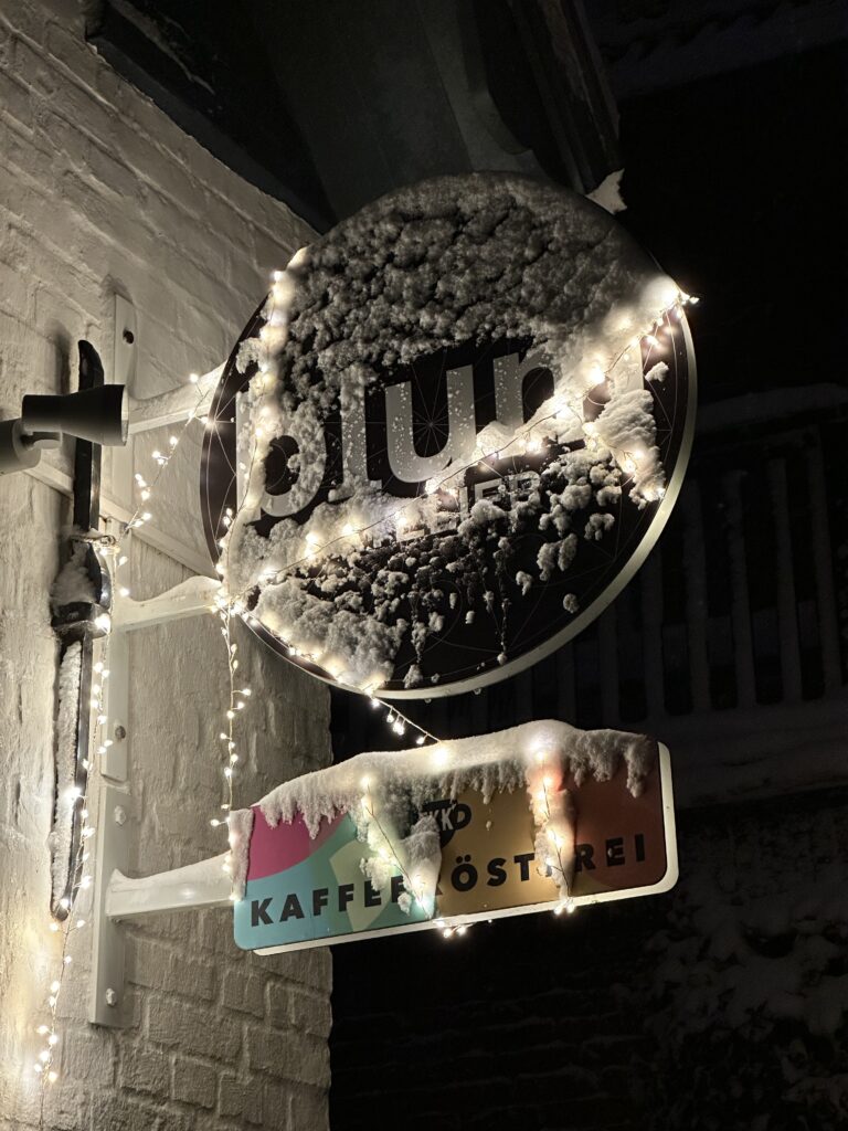 Schneebedecktes Ladenschild von Blum und Karuso, Kaffeerösterei und Upycling-Atelier auf der Insel Föhr