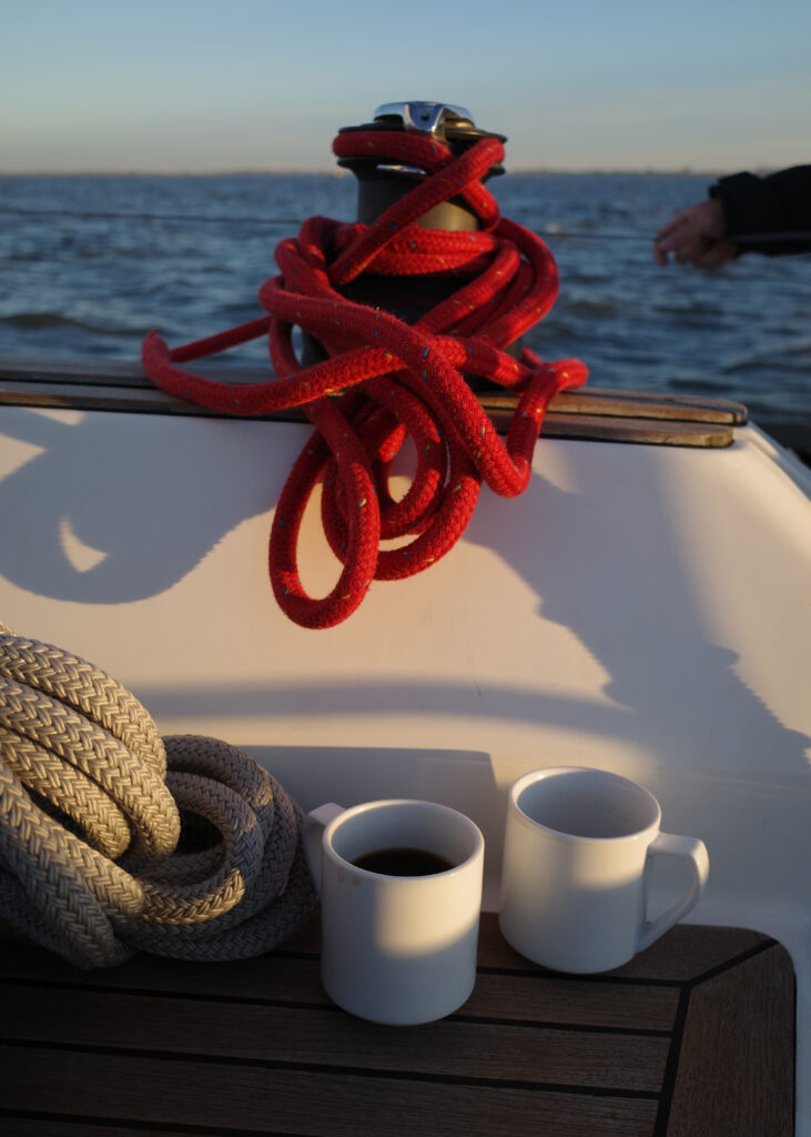 Zwei Kaffeetassen an Bord eines Segelbootes, im Hintergrund die Nordsee